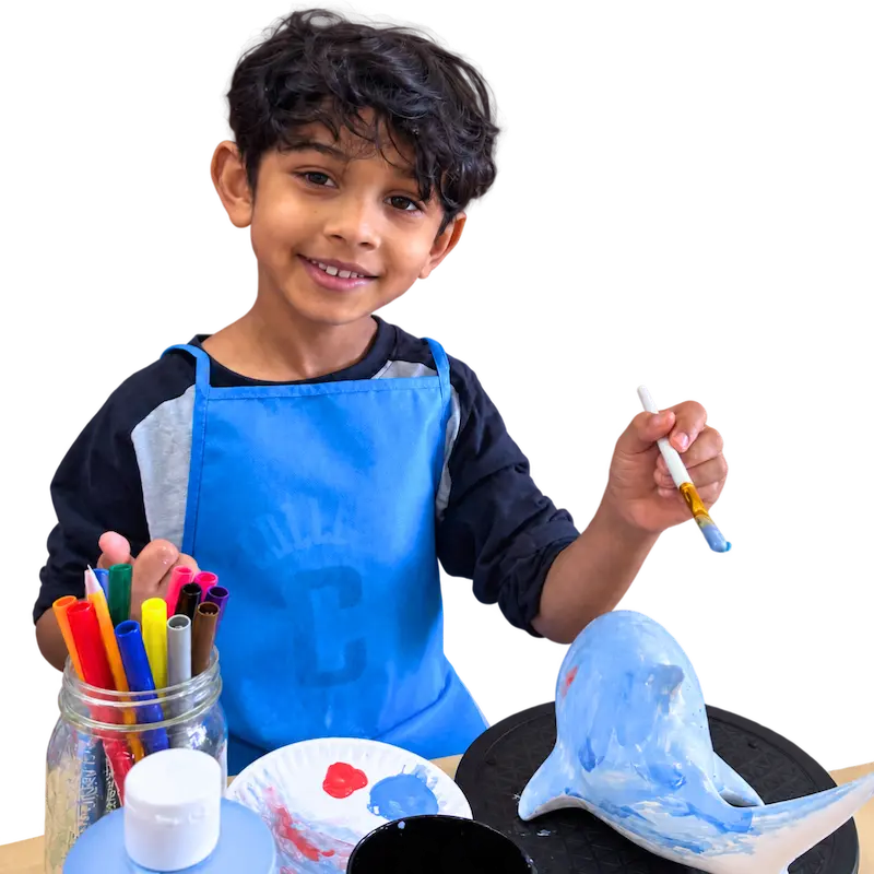 A young child paints pottery at The Hot Spot Studios